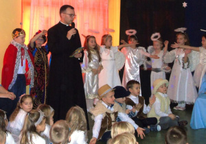 Ksiądz śpiewa, razem z nim dzieci.