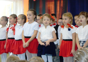 Dziewczynki odświętnie ubrane śpiewają.