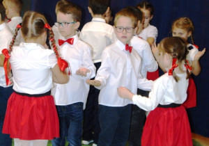 Chłopcy i dziewczynki w parach tańczą.