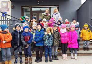 Dzieci stoją na schodach przed budynkim poczty.