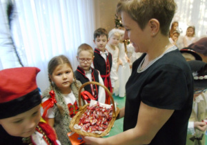 Pani częstuje dzieci cukierkami.