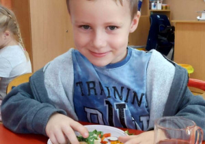 Chłopiec siedzi i trzyma w ręku kanapke.