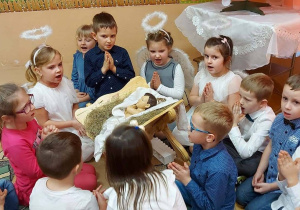 Dzieci siedzą na dywanie i śpiewają.