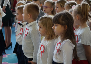 Dzieci na widowni stoją na baczność.
