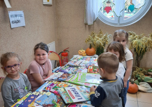 Dzieci oglądają książki leżące na stoliku.
