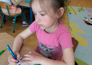 Dziewczynka koloruje mini książeczkę wg własnego projektu.