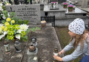 Dziewczynka kładzie znicz na grobi