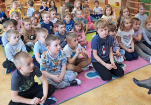 Dzieci siedzą na dywanie.