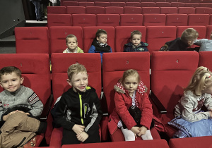 Grupa dzieci siedzi na widowni teatralnej