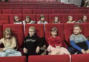 Grupa dzieci siedzi na widowni teatralnej