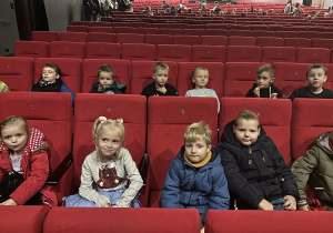Grupa dzieci siedzi na widowni teatralnej