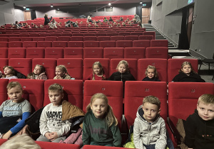 Grupa dzieci siedzi na widowni teatralnej