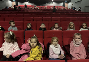 Grupa dzieci siedzi na widowni teatralnej