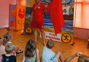 Na zdjęciu jest Pan Ratownik WOPR. Trzyma w ręku czerwoną flagę.