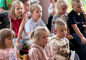 Grupa dzieci z zainteresowaniem patrzy na pokaz występu.