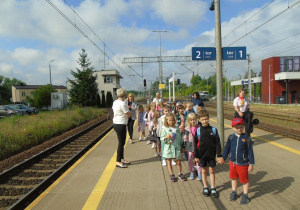 Dzieci wspólnie z nauczycielkami stoją na peronie stacji PKP.