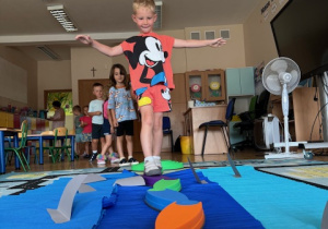 Chłopczyk przechodzi przez przeszkodę za nimi w kolejce ustawione są kolejne dzieci