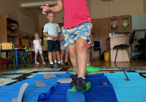 Dziewczynka przechodzi przez przeszkodę za nimi w kolejce ustawione są kolejne dzieci