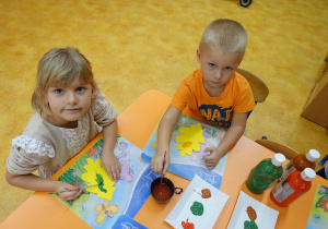 Dziewczynka i chłopiec ozdabiający farbami liście z papieru