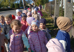 Grupa przedszkolaków idąca chodnikiem wraz z opiekunami