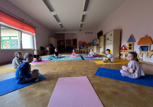 Przedszkolaki siedzące w kole na kolorowych matach do ćwiczeń
