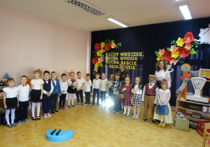 Grupa występujących przedszkolaków wraz z opiekunkami na tle dekoracji