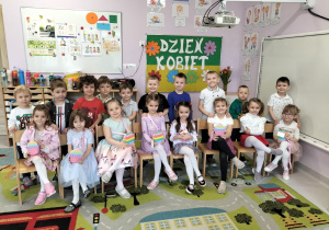 Dziewczynki siedzące na krzesełkach przed grupą chłopców
