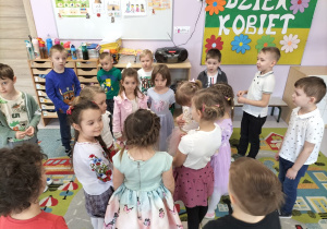 Dziewczynki stojące w kole, dookoła nich chłopcy