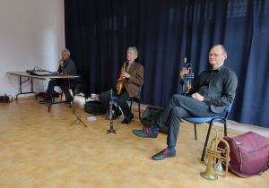 Muzycy filharmonii prezentujący saksofon i trąbkę.