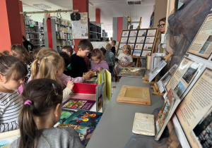Grupa przedszkolaków oglądająca książki dostępne w bibliotece szkolnej.