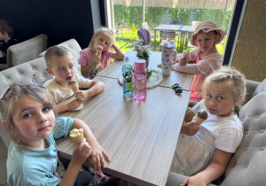 Przedszkolaki jedzące lody przy stoliku w restauracji.
