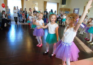 Dzieci tańczą w dwóch rzędach.