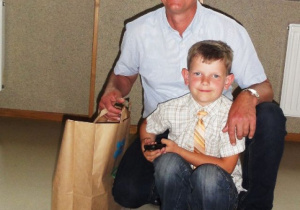Chłopiec wraz ojcem trzynającym torbę z nagrodami kucają