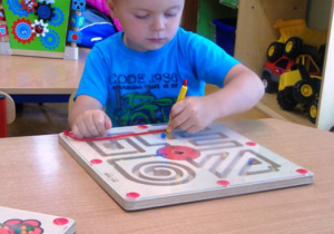 Chłopiec siedzi przy stoliku i bawi się grą