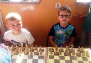 Dwóch chłopców siedzi przy stoliku i grają w szachy