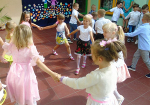Dzieci tańczą w kółeczkach trzymają się za ręce
