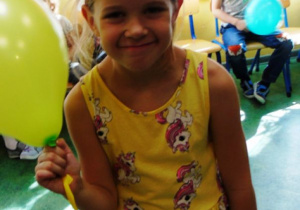 Dziewczynka trzyma żółty balon.