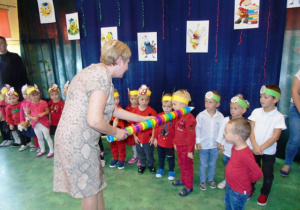 Kobieta kolorowym ołówkiem dotyka dzieci o ramieniu.