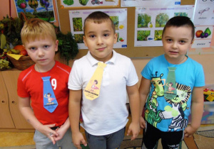 Trzech chłopców ma na szyi krawaty z napisami "Super chłopak".