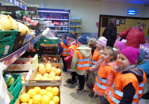 Dzieci w sklepie patrzą na owoce.