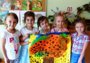 Dziewczynki trzymają plakat z namalowanym drzewem.