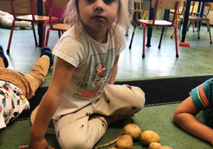 Dziewczynka układa z ziemniaków figurę.