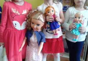 Dziewczynki trzymają lalki.