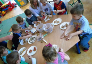 Dzieci przy stolikach ozdabiają pierniki.