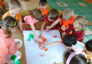 Dzieci malują obrazek marchewki.