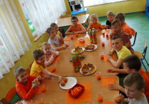 Dzieci siedzą przy stole i jedzą.