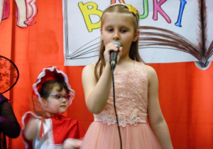 Dziewczynka śpiewa do mikrofonu.