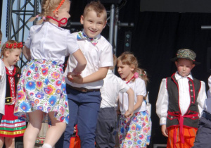 Dzieci tańczą trzymając się za ręce.