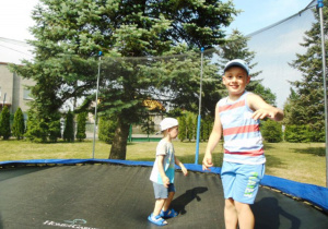 Dwóch chłopców skacze na trampolinie.