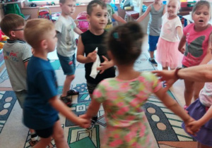Dzieci trzymają się za rączki i tańczą w kółeczki